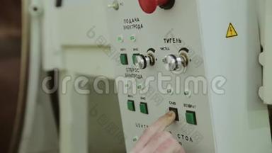 工人`手按动工厂机器控制面板上的按钮。